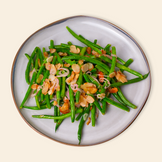 A plate of Green Beans Almondine, with green beans tossed with almonds and a light buttery vegan sauce, served on a grey plate.